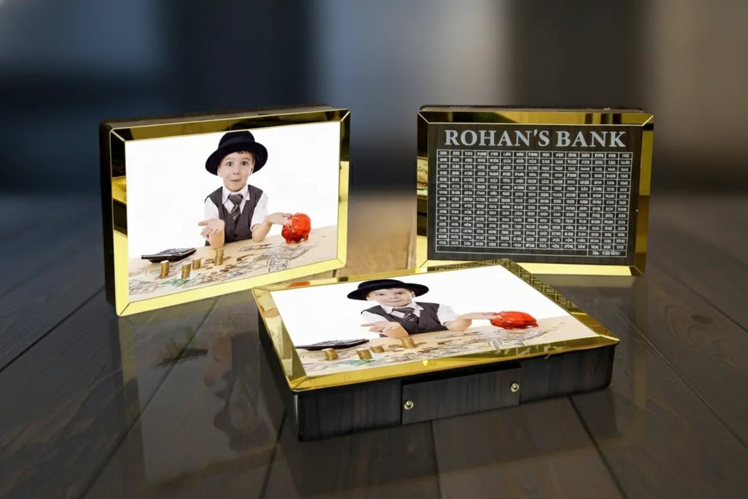 A custom wooden and gold photo box set displayed on a dark wooden table. The set includes a closed box with a photo of a young boy in a hat, an open drawer showing a printed insert, and a separate gold-framed plaque labeled &